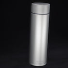 Slim titanium insulated bottle, 450 ml, standing on black with its flat lid on