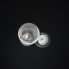 The open bottle from above, the lid and tea strainer beside it