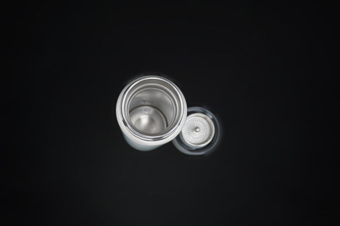 The open bottle from above, the lid and tea strainer beside it
