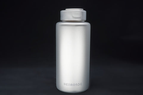 Titanium sport bottle, 1000 ml, standing on black, the HEXMONDE wordmark near the base