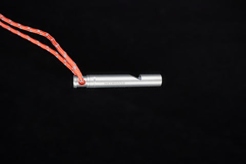 The whistle lying on its side, the lanyard looped through its end