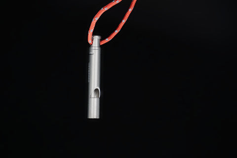 Titanium whistle hanging from its orange lanyard