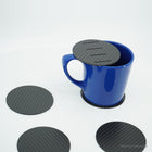 Slotted carbon fiber coaster resting on a blue mug, three coasters around it