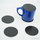Five carbon fiber coasters, the slotted one on a blue mug as a cover