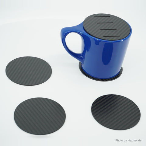 Five carbon fiber coasters, the slotted one on a blue mug as a cover