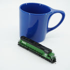 Cascade Green Burlington Northern SD45 locomotive beside a blue mug for scale; mug is not included.